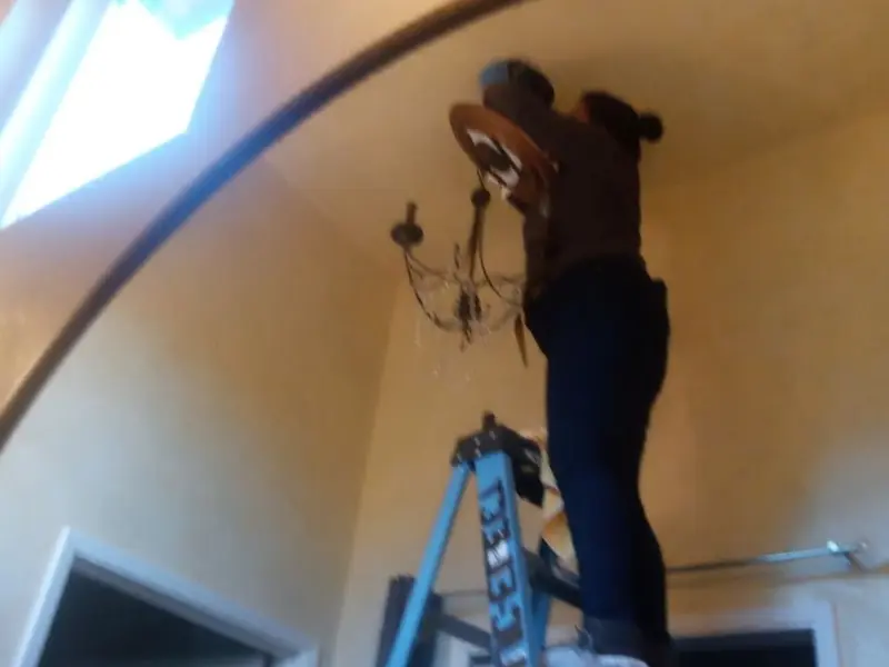 Electrician installing a chandelier in a Cramerton residence